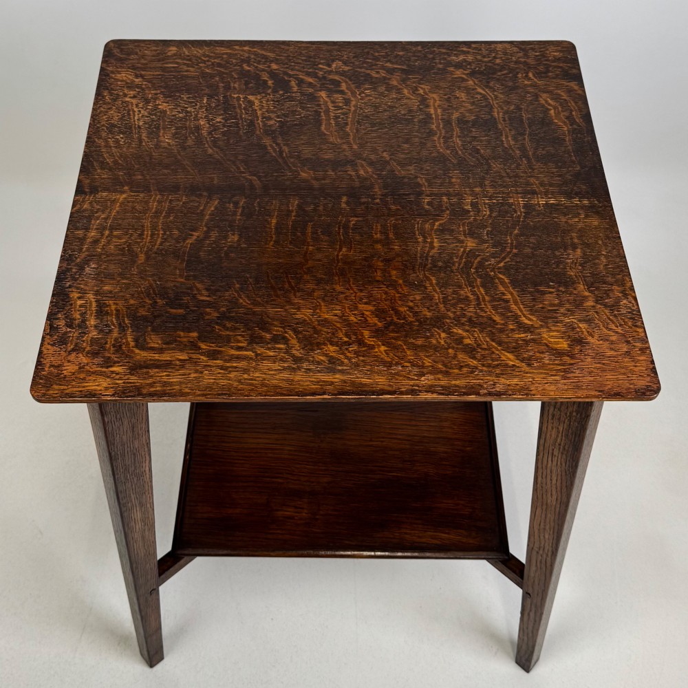 An Edwardian dark oak side table featuring a square top, cross-stretchers, tapered legs, and a lower square shelf. View IX