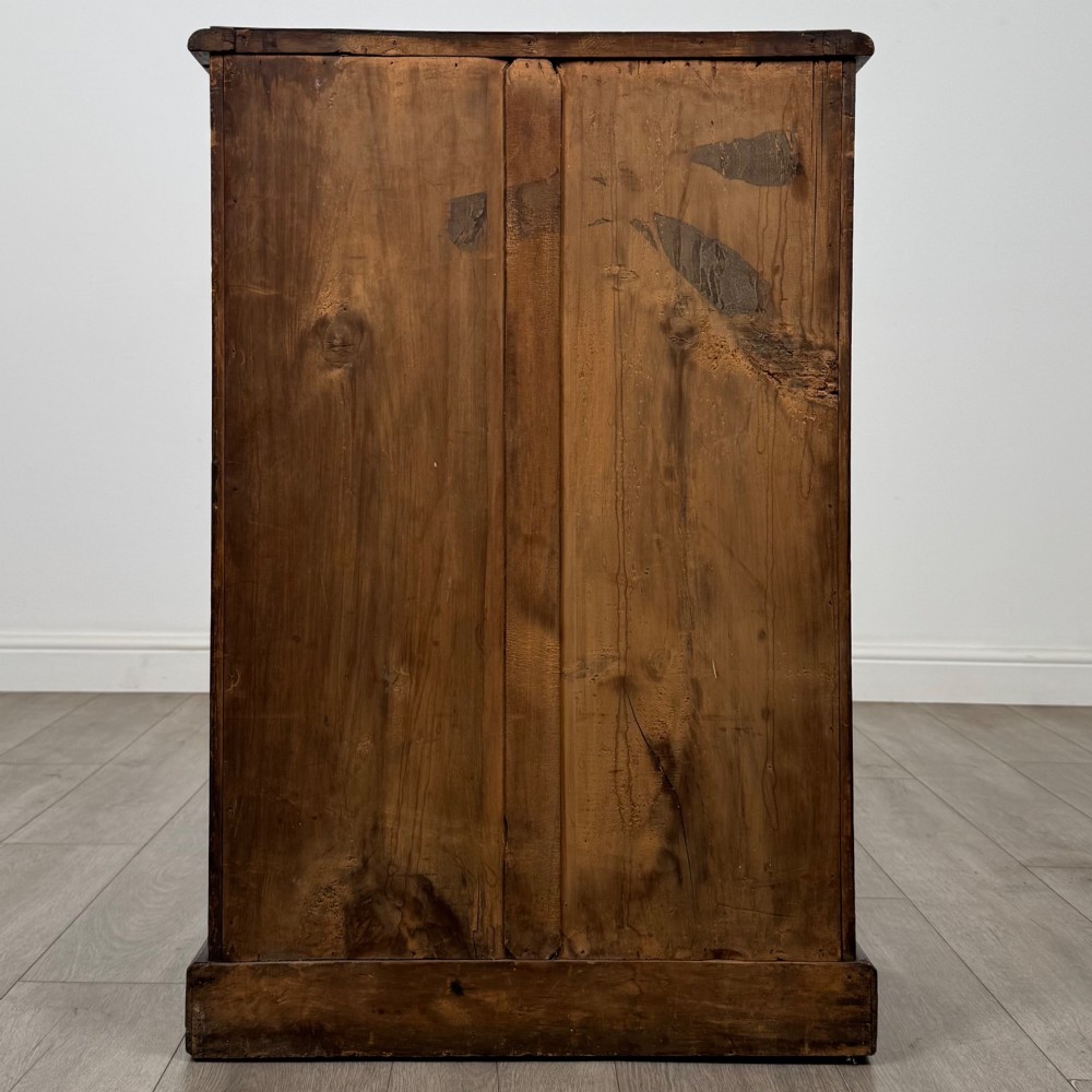 A nineteenth-century mahogany display cabinet featuring twin glazed doors with arched framing and a plinth base. View VI