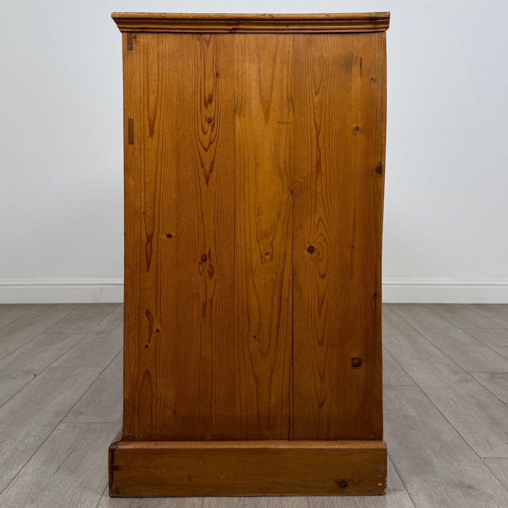 A vintage pine farmhouse sideboard featuring three frieze drawers above three panelled cupboard doors with turned wooden knobs on a plinth base. View IV