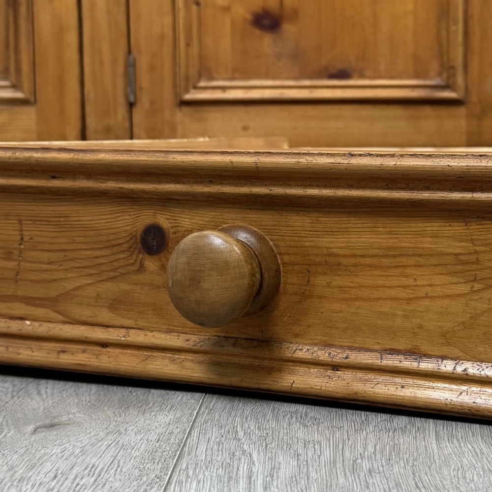 A vintage pine farmhouse sideboard featuring three frieze drawers above three panelled cupboard doors with turned wooden knobs on a plinth base. View XII