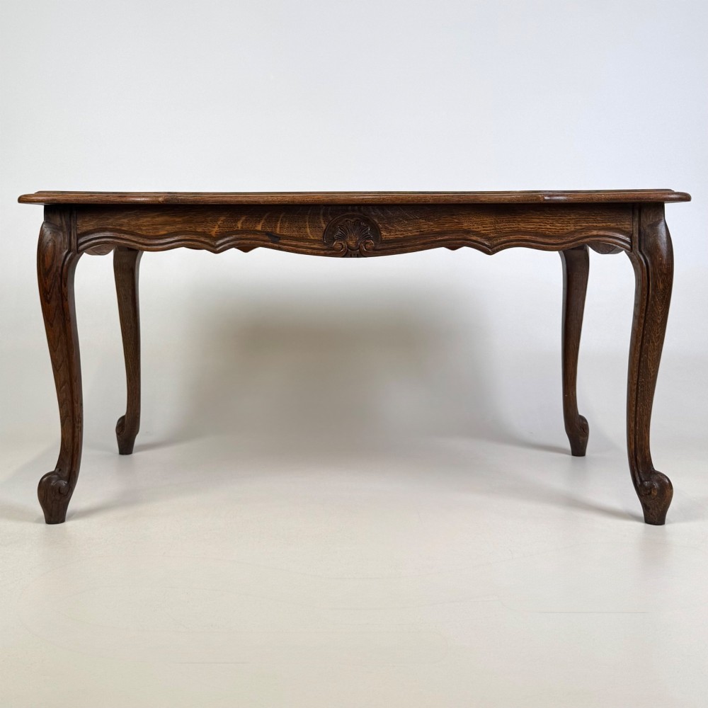 A 20th-century dark oak coffee table featuring cabriole legs, a serpentine apron, and a central carved shell motif.