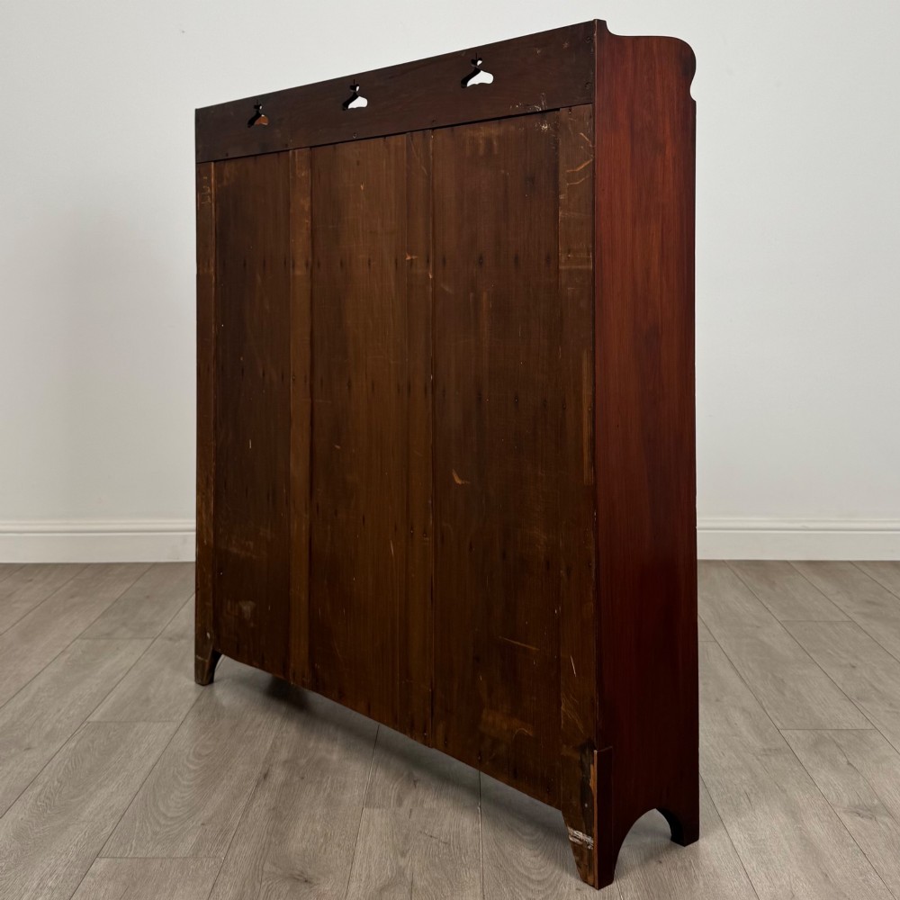 An early 20th-century Arts and Crafts open walnut bookcase featuring four shelves and decorative pierced cut-outs on the top gallery and plinth base. View VII