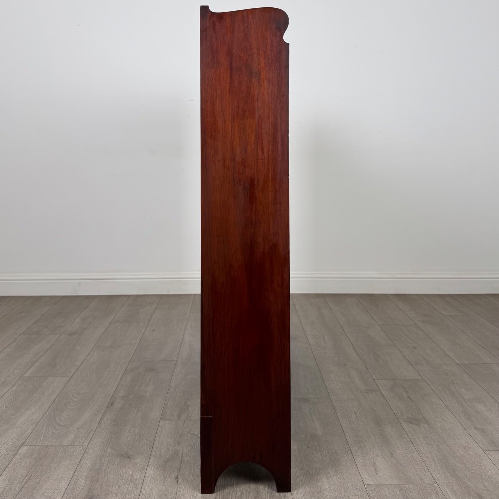 An early 20th-century Arts and Crafts open walnut bookcase featuring four shelves and decorative pierced cut-outs on the top gallery and plinth base. View VIII