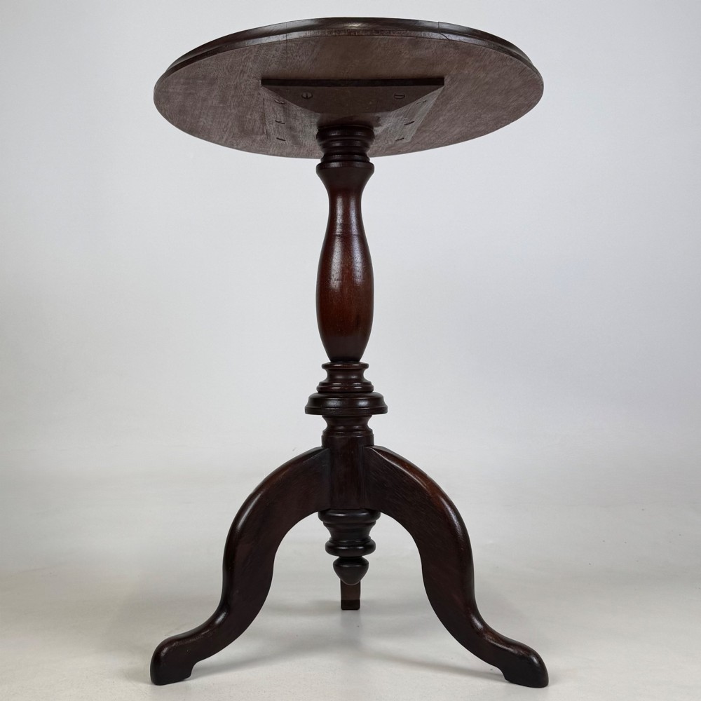 An antique dark mahogany side table featuring a smooth oval top, a centrally turned pedestal stem, and three splayed tripod legs. View III