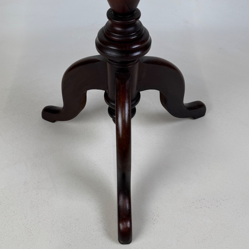 An antique dark mahogany side table featuring a smooth oval top, a centrally turned pedestal stem, and three splayed tripod legs. View VII
