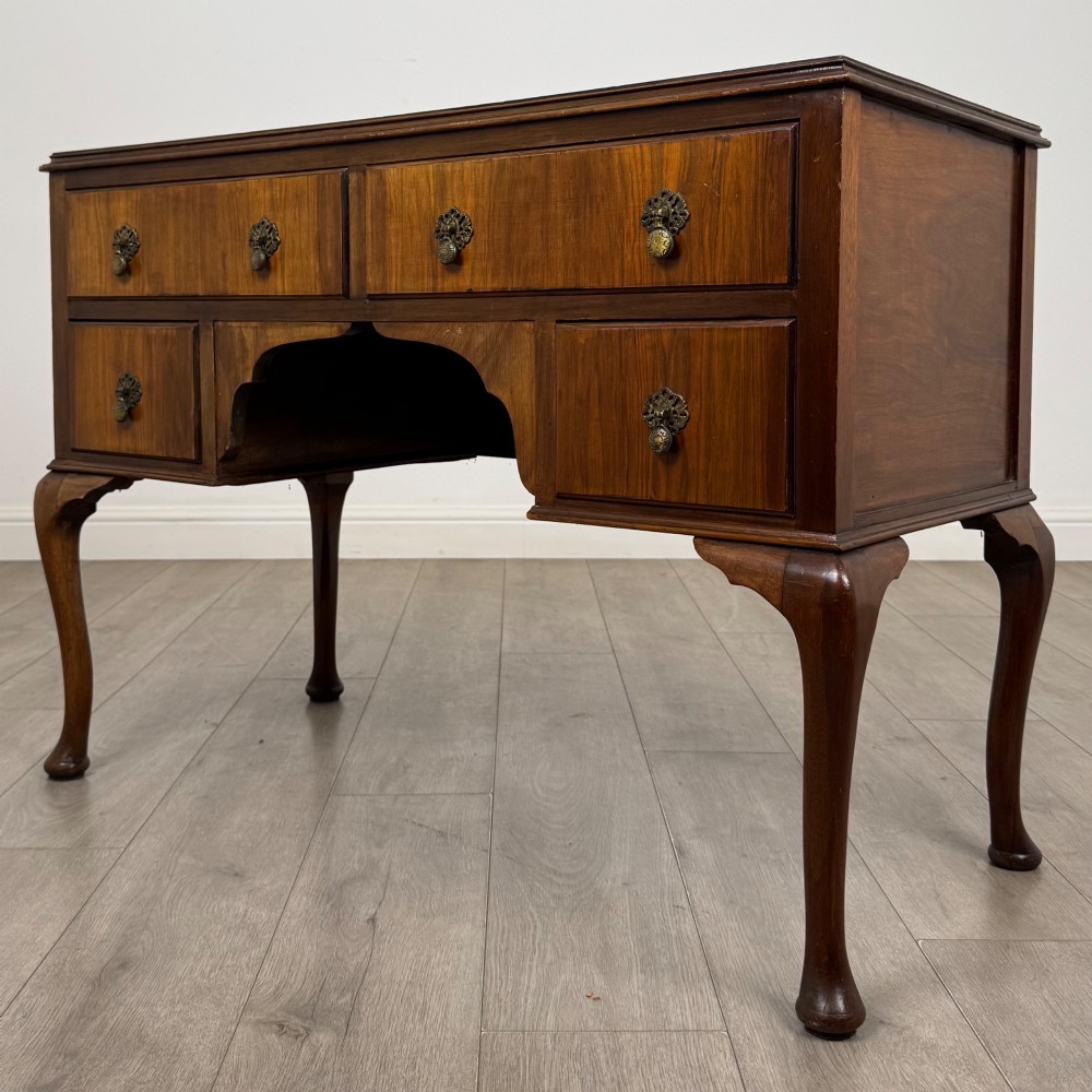 A 20th-century walnut writing table featuring four drawers, decorative brass drop handles, an arched kneehole centre, and curved cabriole legs. View II