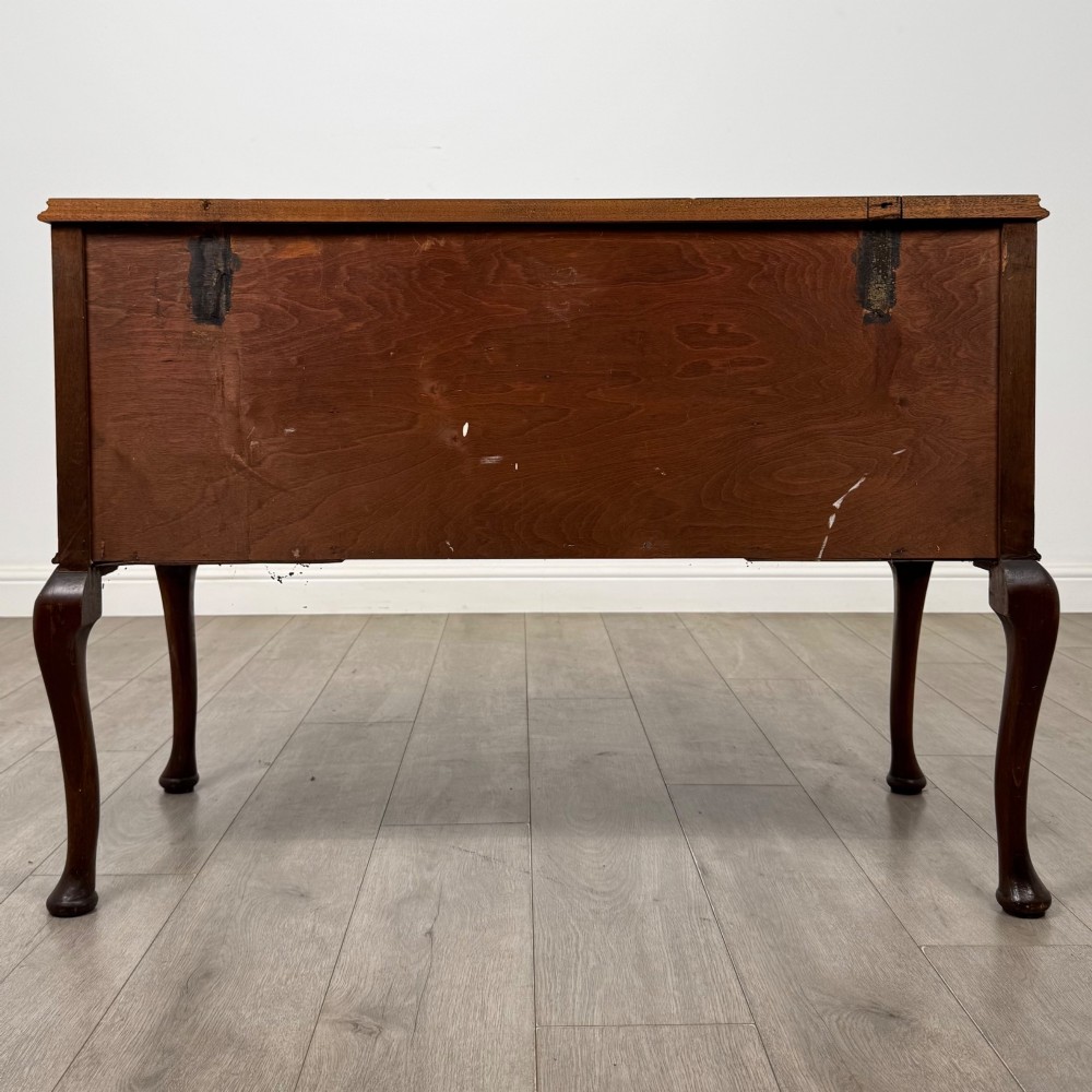 A 20th-century walnut writing table featuring four drawers, decorative brass drop handles, an arched kneehole centre, and curved cabriole legs. View V