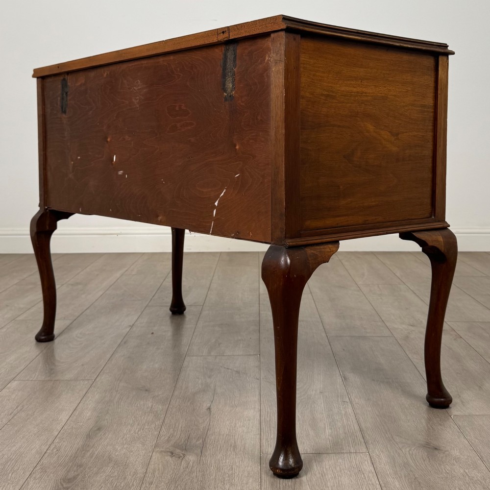 A 20th-century walnut writing table featuring four drawers, decorative brass drop handles, an arched kneehole centre, and curved cabriole legs. View VI