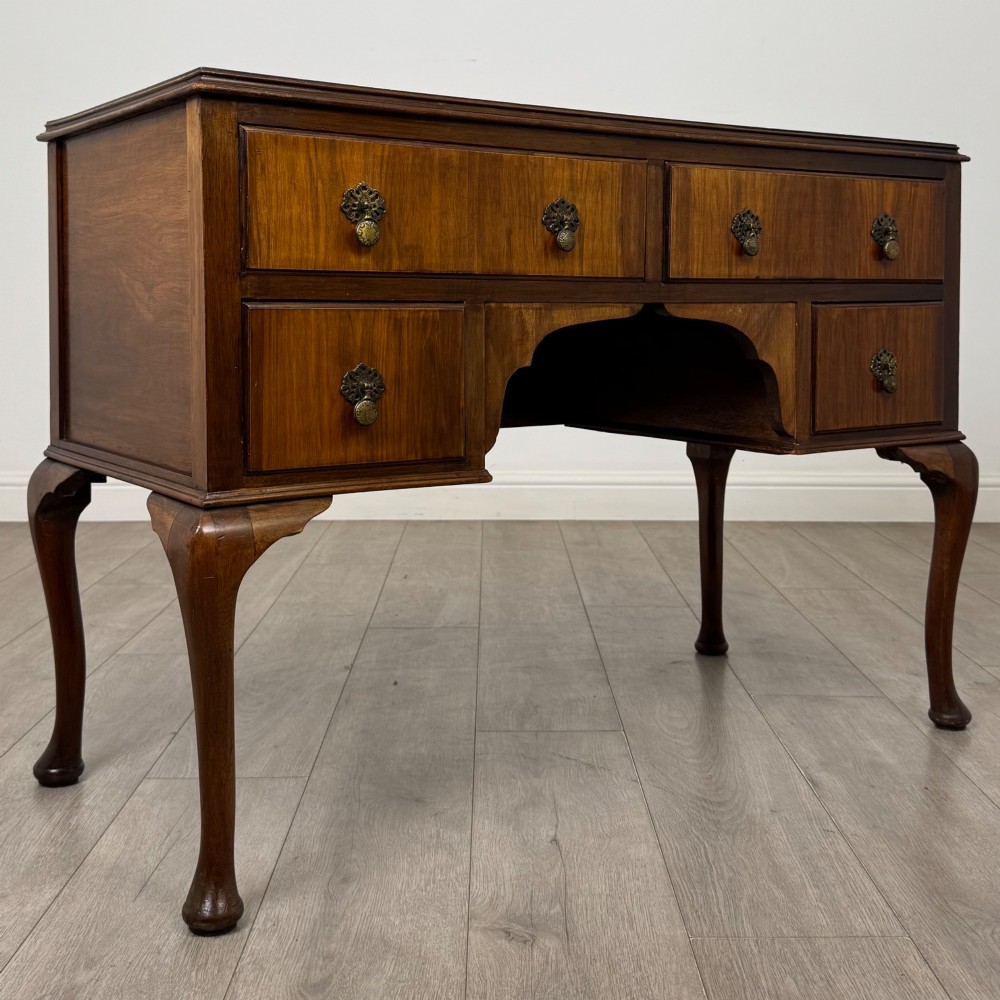 A 20th-century walnut writing table featuring four drawers, decorative brass drop handles, an arched kneehole centre, and curved cabriole legs. View VIII