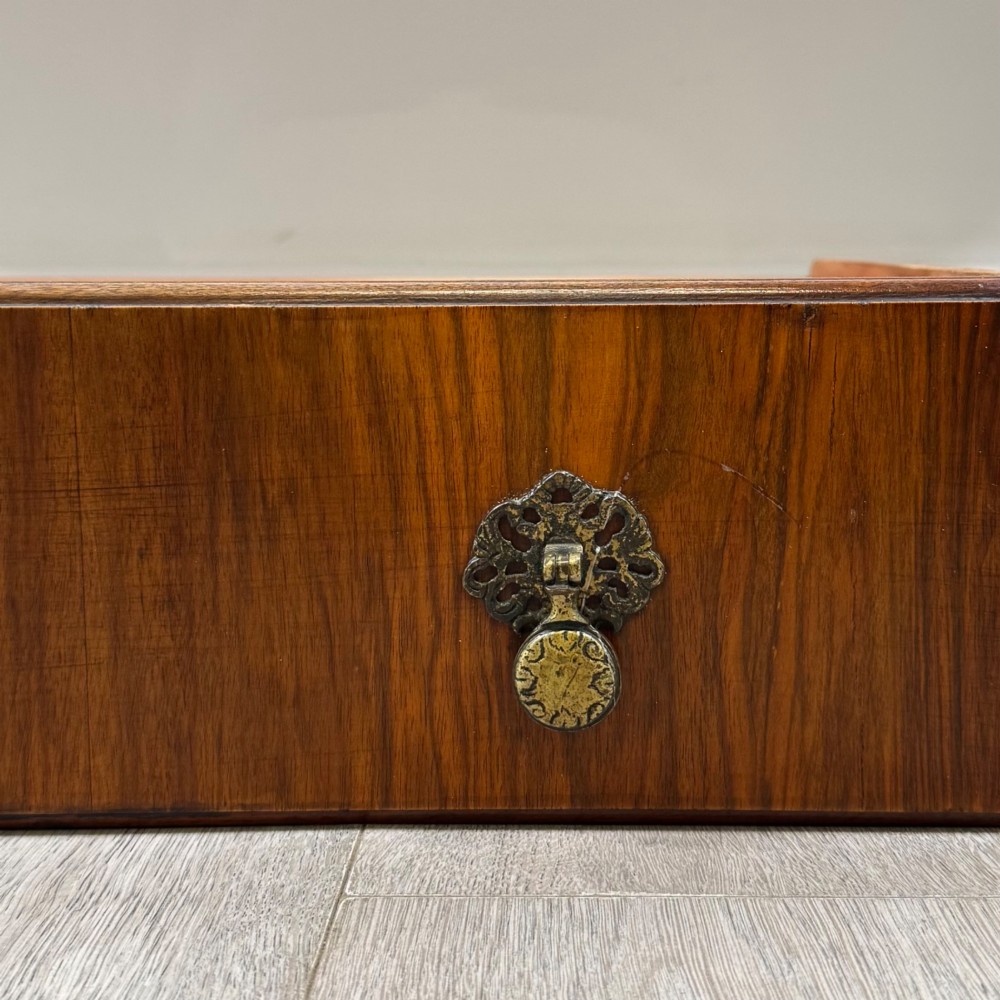 A 20th-century walnut writing table featuring four drawers, decorative brass drop handles, an arched kneehole centre, and curved cabriole legs. View XI