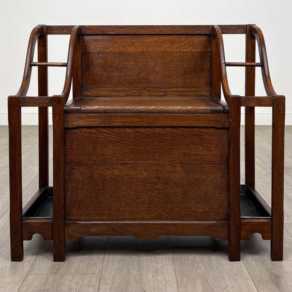 An antique Edwardian golden oak hall seat featuring a central panelled backrest and integrated side umbrella stands with metal drip trays.