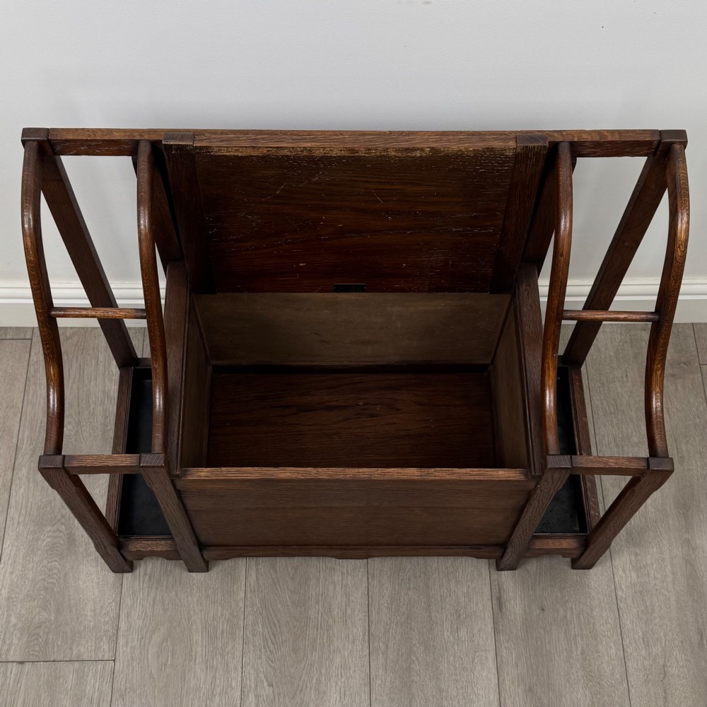 An antique Edwardian golden oak hall seat featuring a central panelled backrest and integrated side umbrella stands with metal drip trays. View X