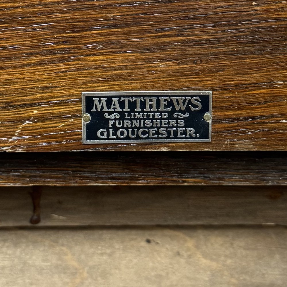 An antique Edwardian golden oak hall seat featuring a central panelled backrest and integrated side umbrella stands with metal drip trays. View XI