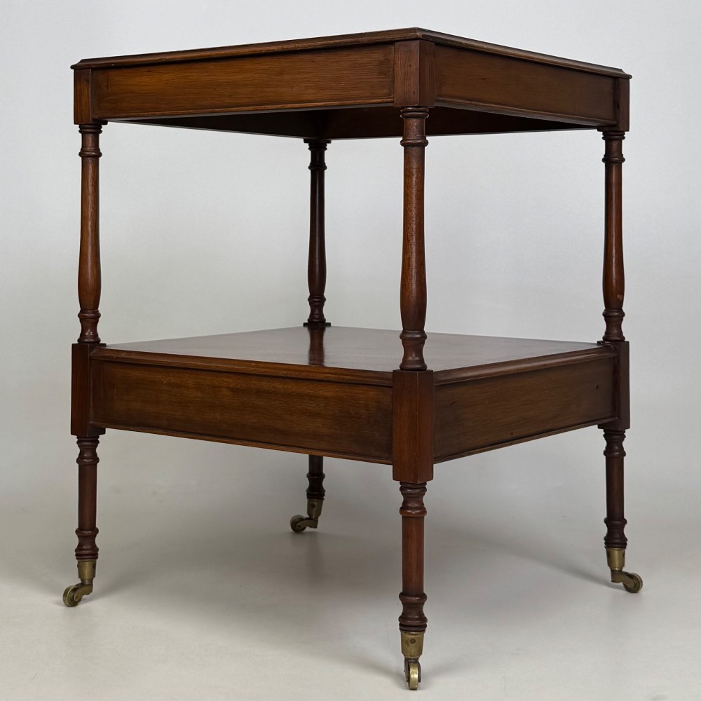 A pair of 20th-century warm mahogany bedside tables featuring turned support pillars, open middle shelves, single lower drawers with brass handles, and brass castors. View V