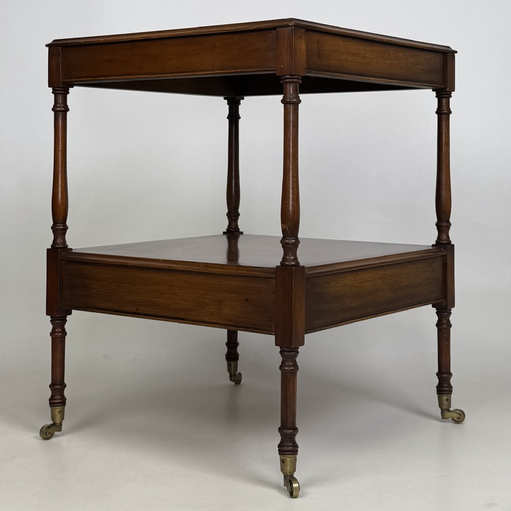 A pair of 20th-century warm mahogany bedside tables featuring turned support pillars, open middle shelves, single lower drawers with brass handles, and brass castors. View VII