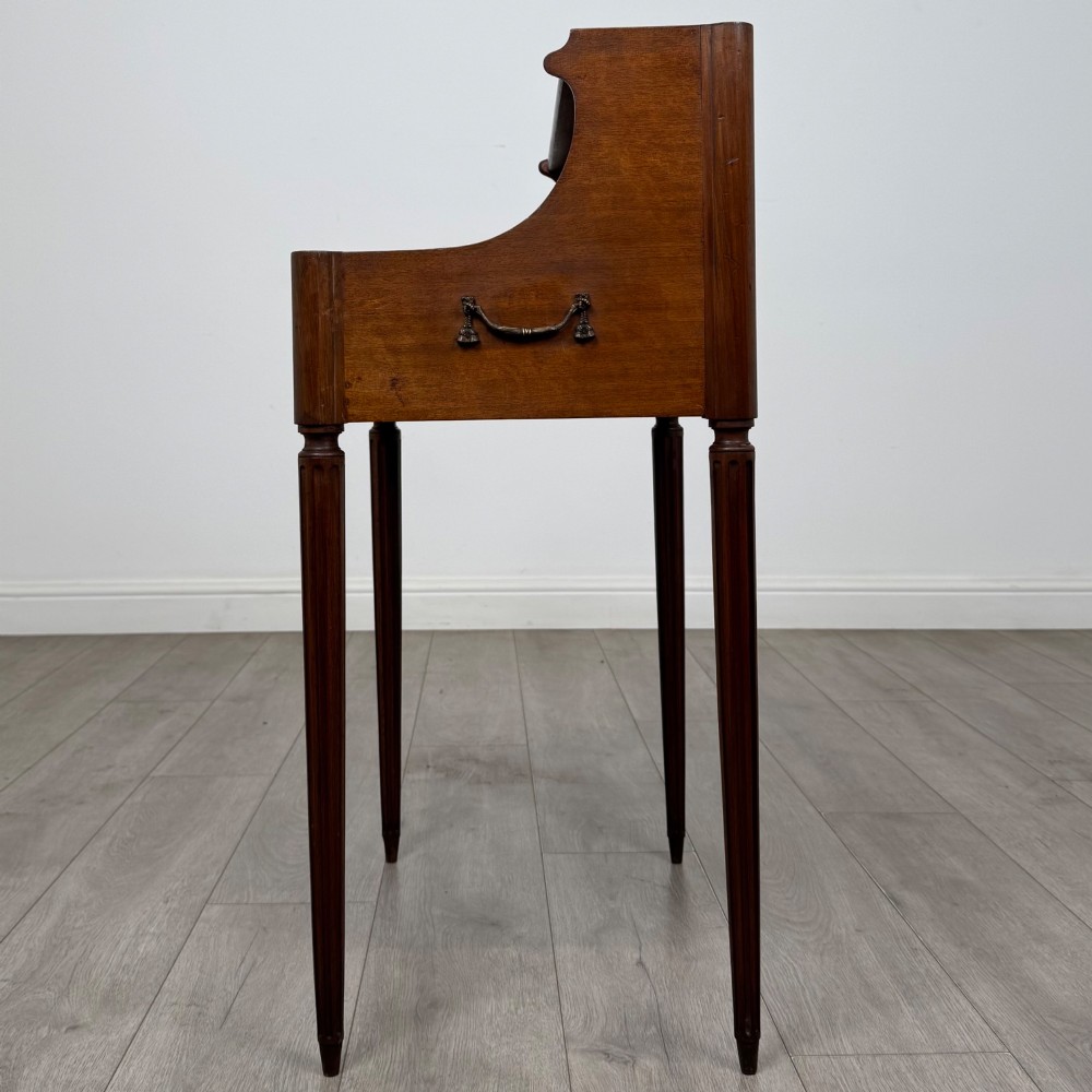 A French mahogany side table featuring slim tapered fluted legs, a carved laurel motif apron, and a gallery back adorned with brass stars. View III