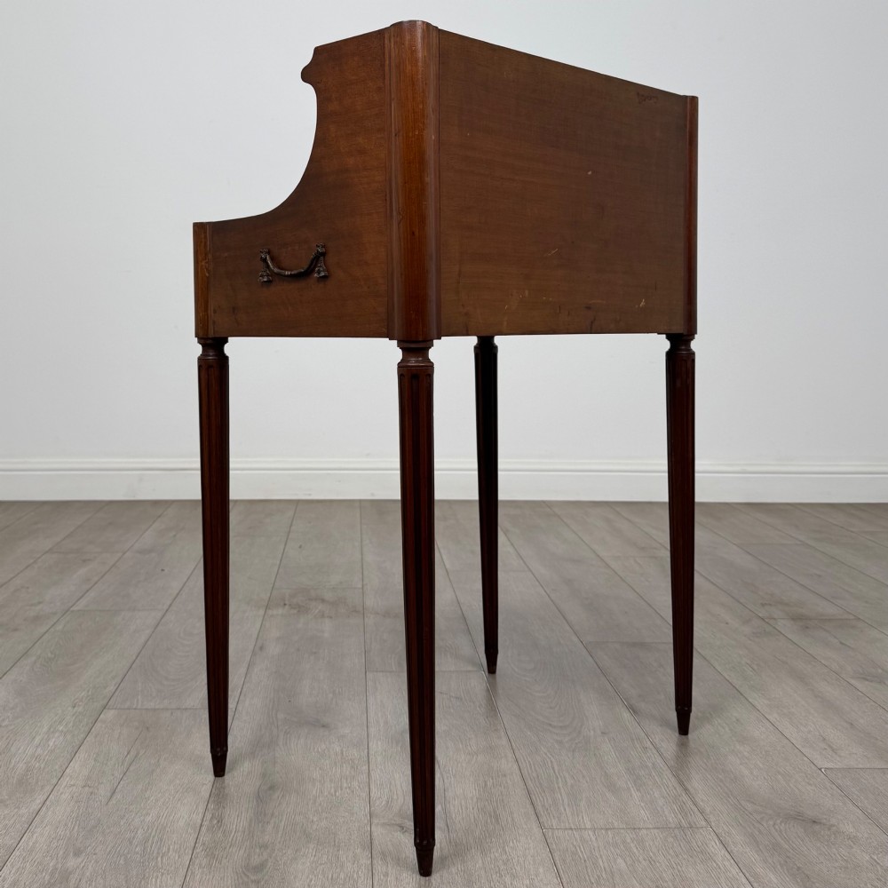 A French mahogany side table featuring slim tapered fluted legs, a carved laurel motif apron, and a gallery back adorned with brass stars. View IV