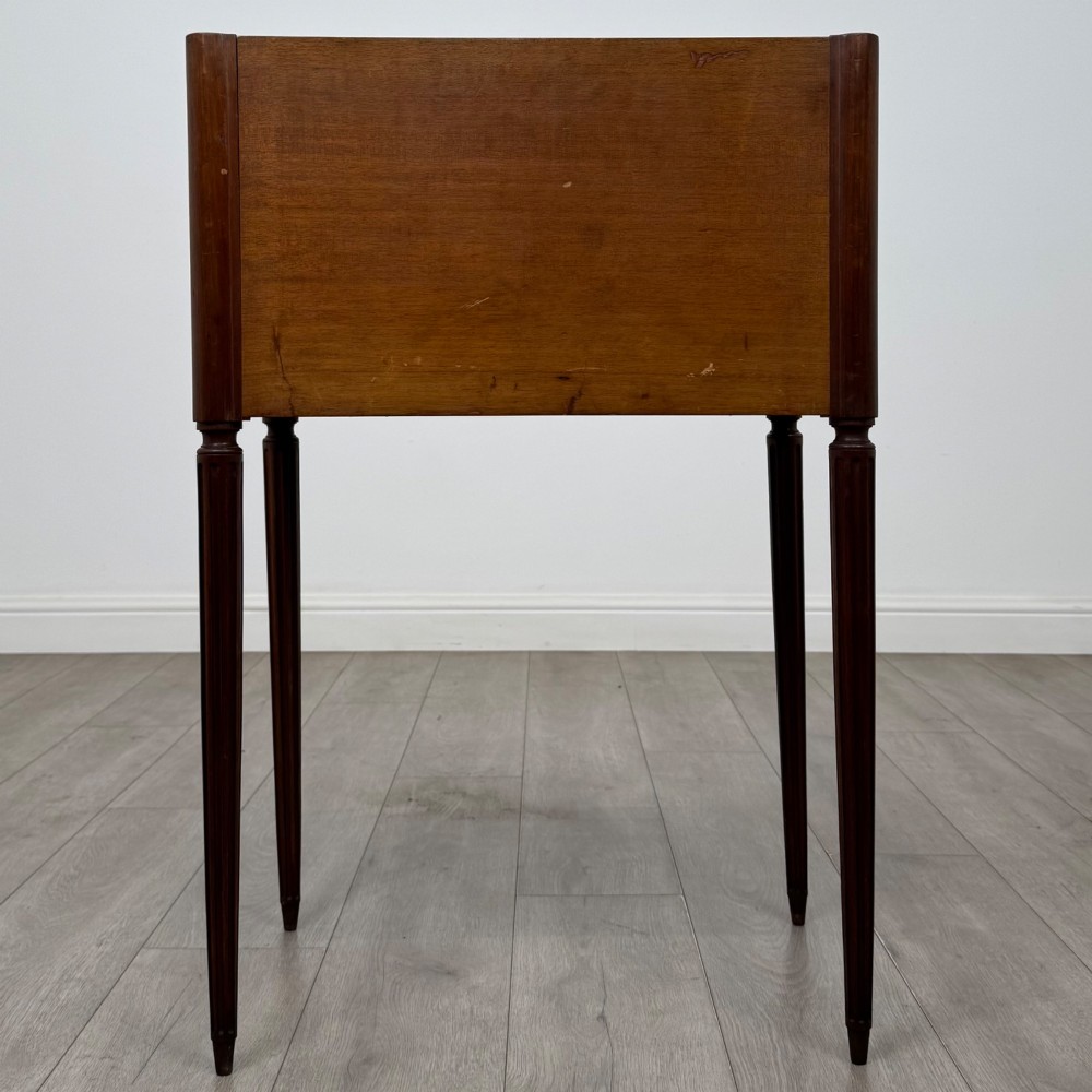 A French mahogany side table featuring slim tapered fluted legs, a carved laurel motif apron, and a gallery back adorned with brass stars. View V