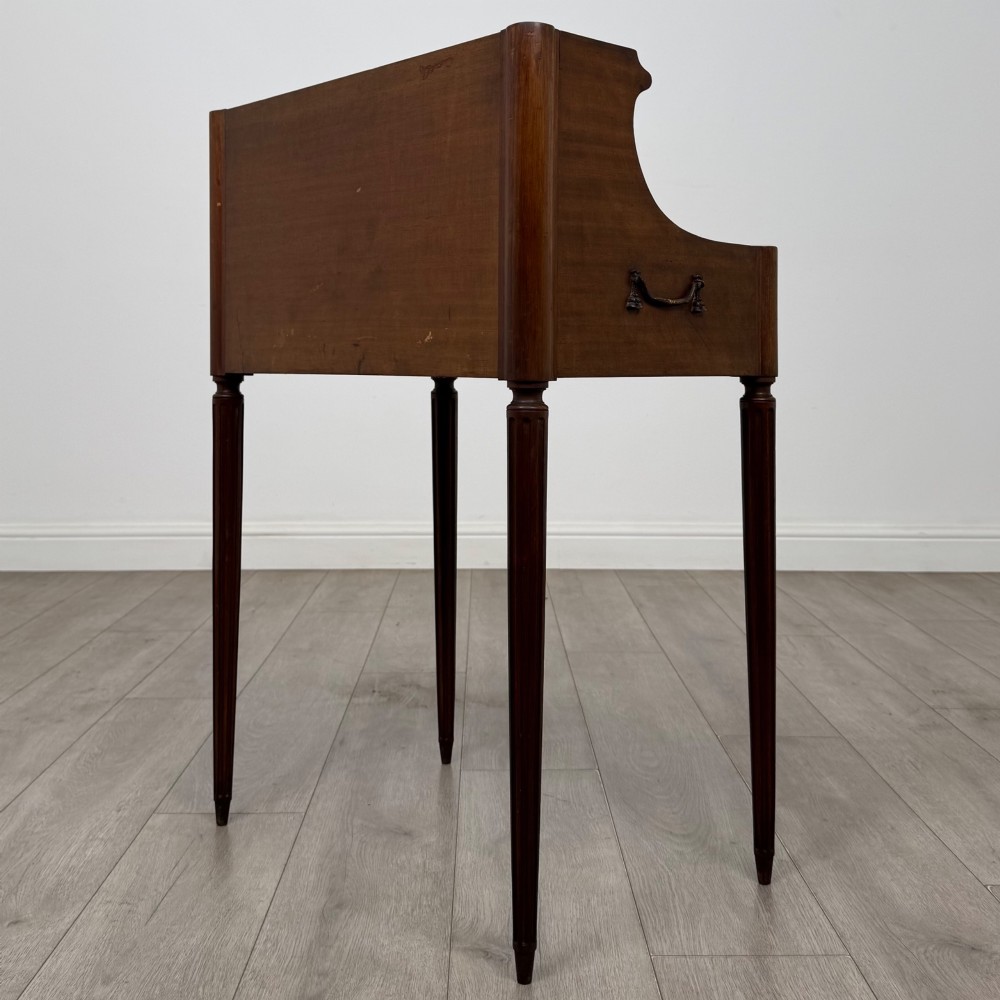 A French mahogany side table featuring slim tapered fluted legs, a carved laurel motif apron, and a gallery back adorned with brass stars. View VI