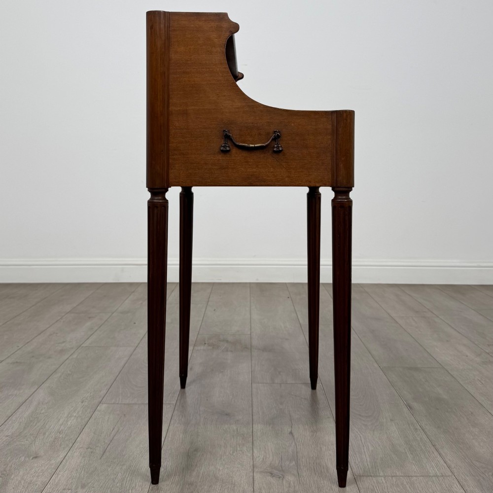 A French mahogany side table featuring slim tapered fluted legs, a carved laurel motif apron, and a gallery back adorned with brass stars. View VII