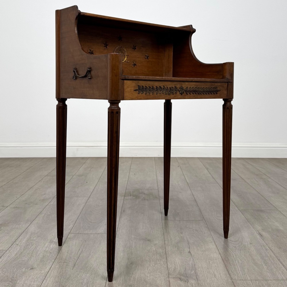 A French mahogany side table featuring slim tapered fluted legs, a carved laurel motif apron, and a gallery back adorned with brass stars. View VIII