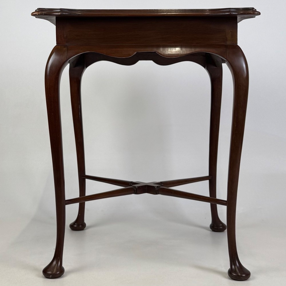 An Edwardian mahogany side table featuring elegant cabriole legs, a shaped apron, and a central X-frame stretcher.