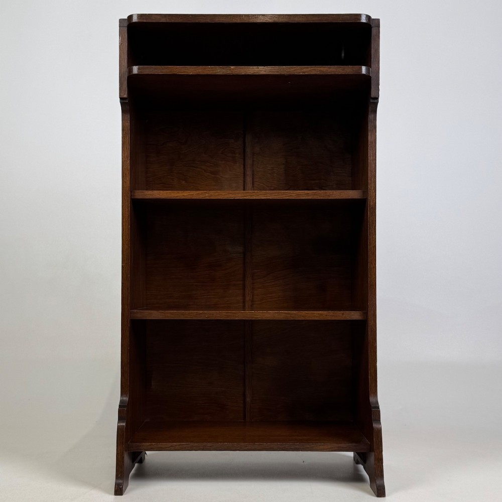 A small Edwardian open bookcase crafted from dark oak timber featuring three open shelves and a shaped apron base. View II
