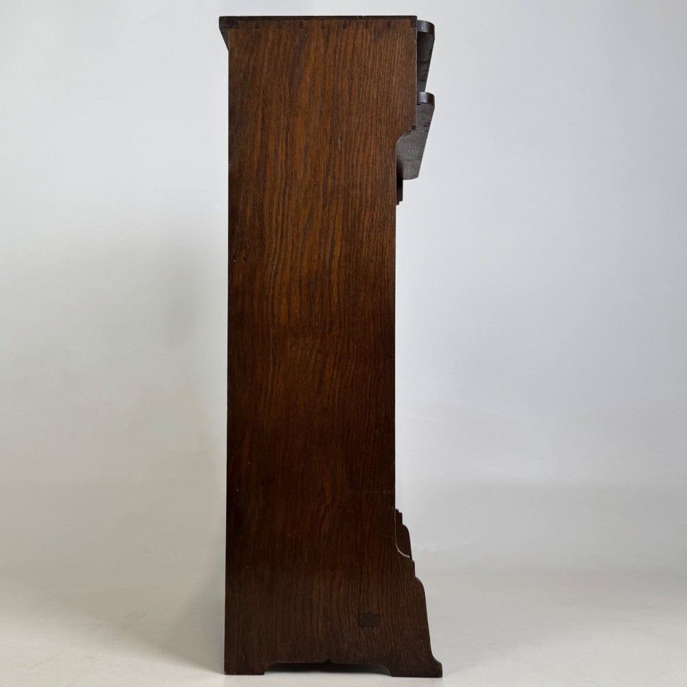 A small Edwardian open bookcase crafted from dark oak timber featuring three open shelves and a shaped apron base. View VIII
