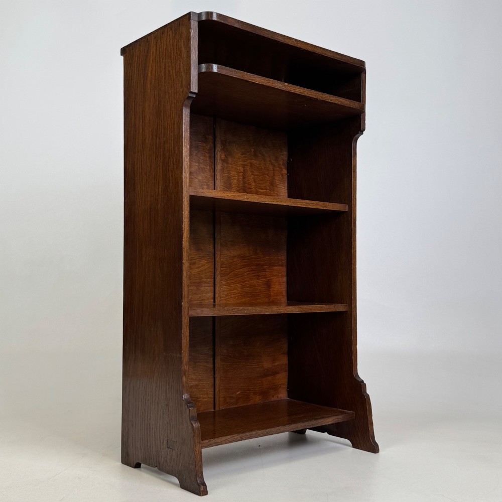A small Edwardian open bookcase crafted from dark oak timber featuring three open shelves and a shaped apron base. View IX