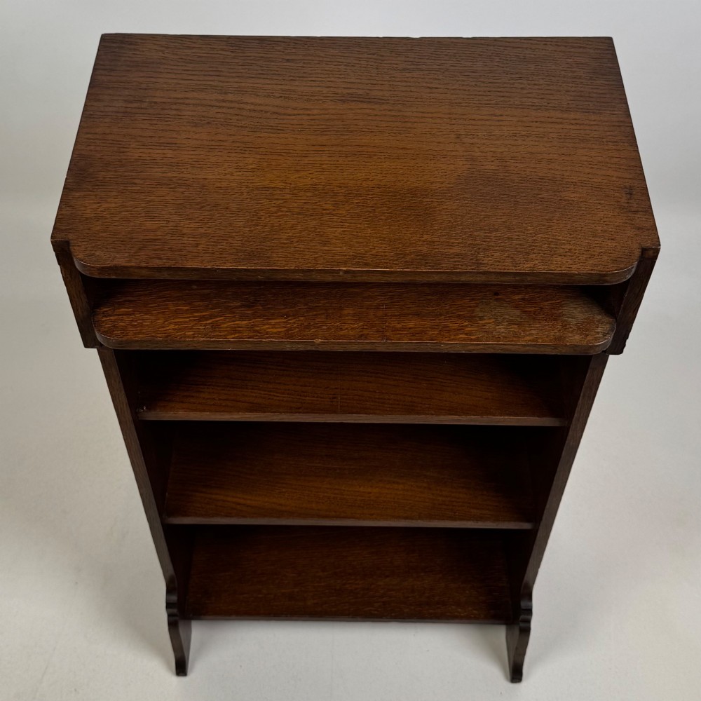 A small Edwardian open bookcase crafted from dark oak timber featuring three open shelves and a shaped apron base. View X