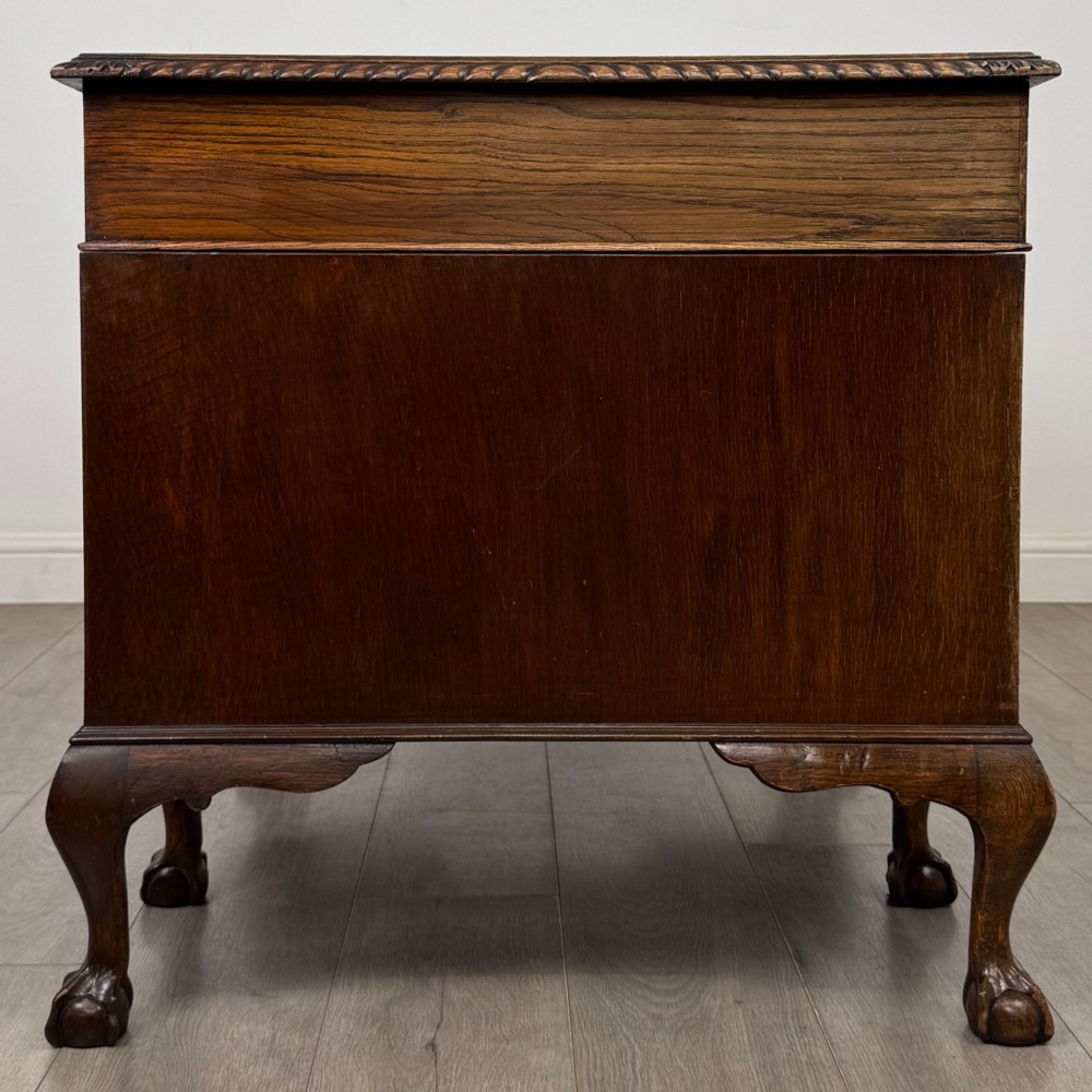 An antique oak pedestal desk featuring twin drawer pedestals, carved borders, and cabriole legs terminating in ball-and-claw feet. View VII