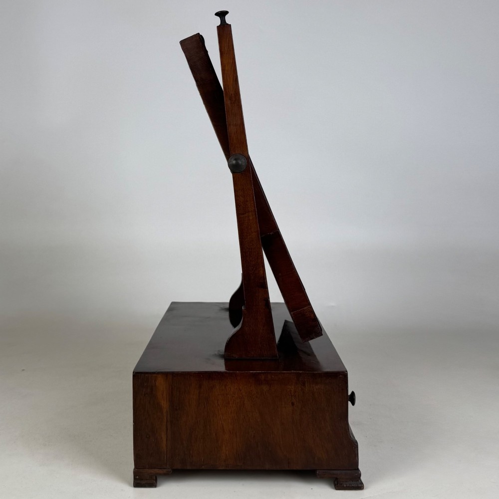 An 18th-century Georgian mahogany dressing mirror featuring an adjustable rectangular tilting glass plate supported above a shaped box base containing three small drawers. View VIII