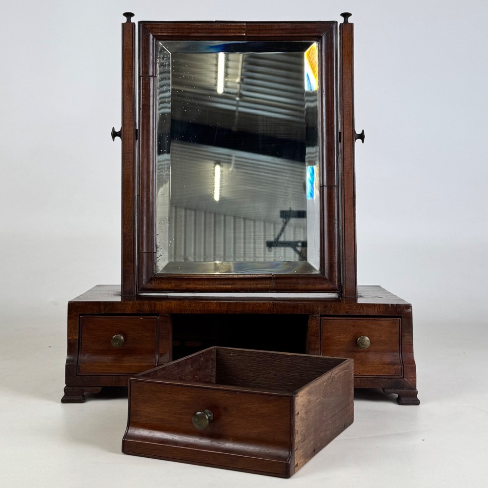 An 18th-century Georgian mahogany dressing mirror featuring an adjustable rectangular tilting glass plate supported above a shaped box base containing three small drawers. View XI