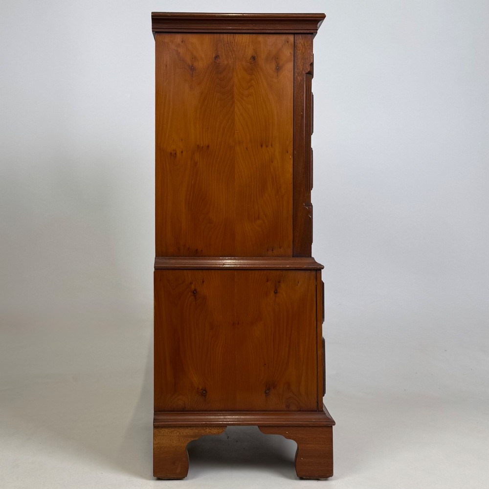 A small yew wood chest of drawers featuring a stepped tallboy structure with brass ring handles and bracket feet. View VII