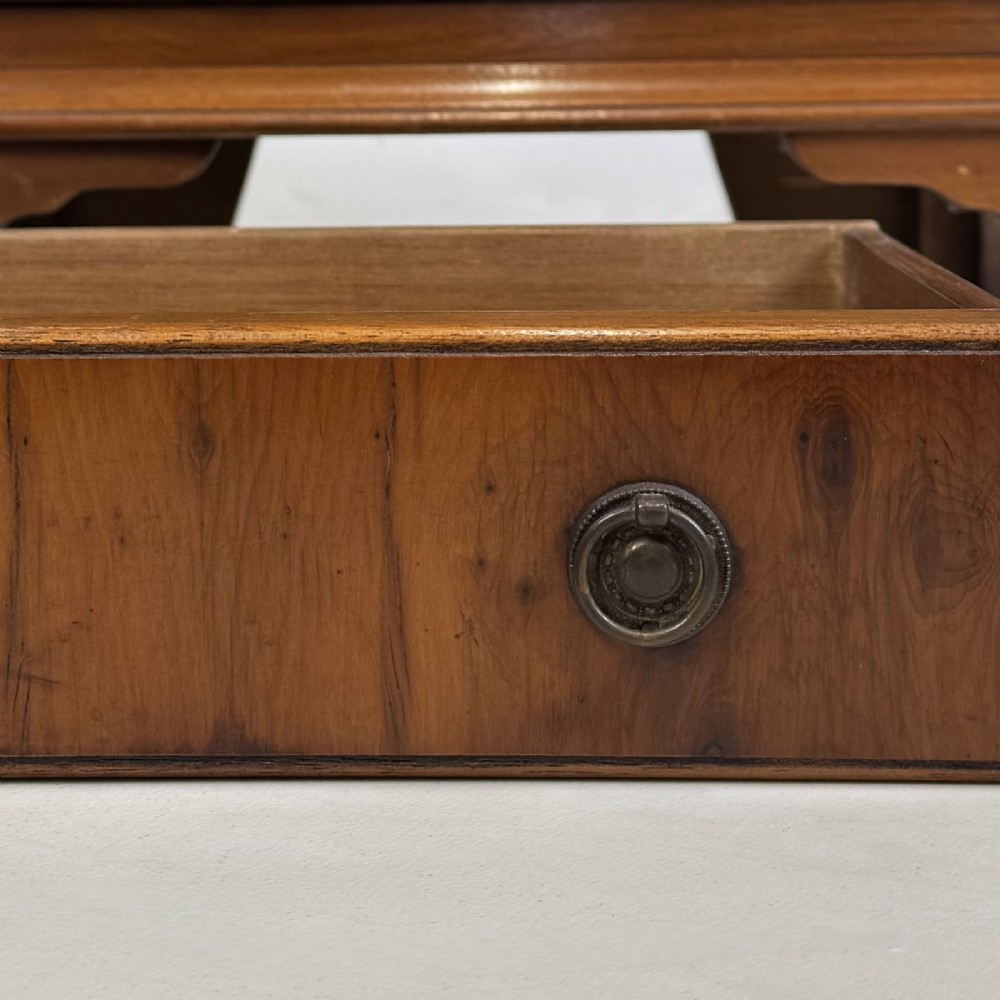 A small yew wood chest of drawers featuring a stepped tallboy structure with brass ring handles and bracket feet. View X