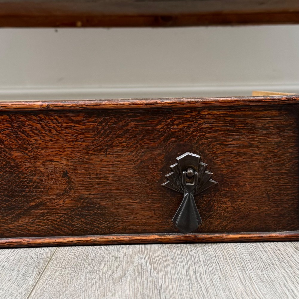 A dark oak sideboard featuring two carved drawers above a double-door cupboard resting on turned legs. View XII
