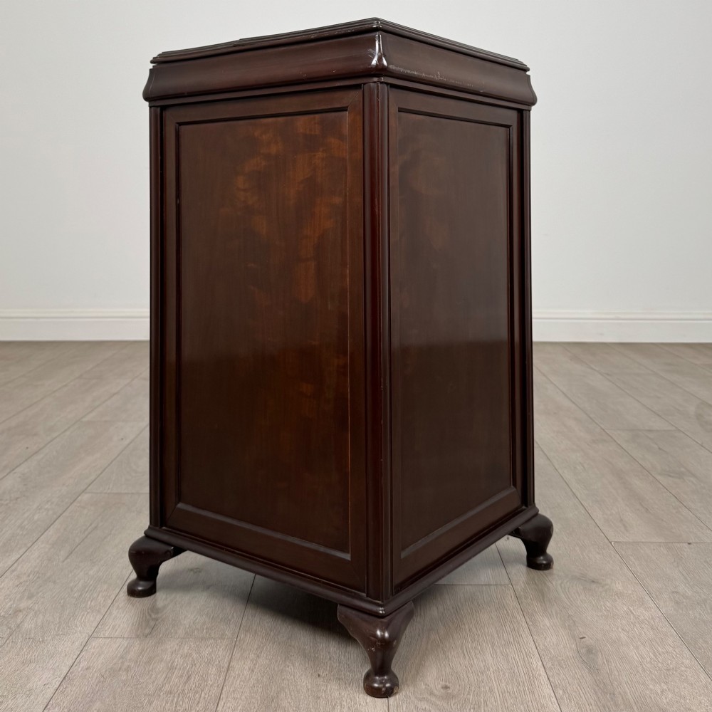 An early 20th-century dark mahogany cupboard featuring two panelled doors with small wooden turned knobs, keyhole escutcheon, and cabriole feet. View V