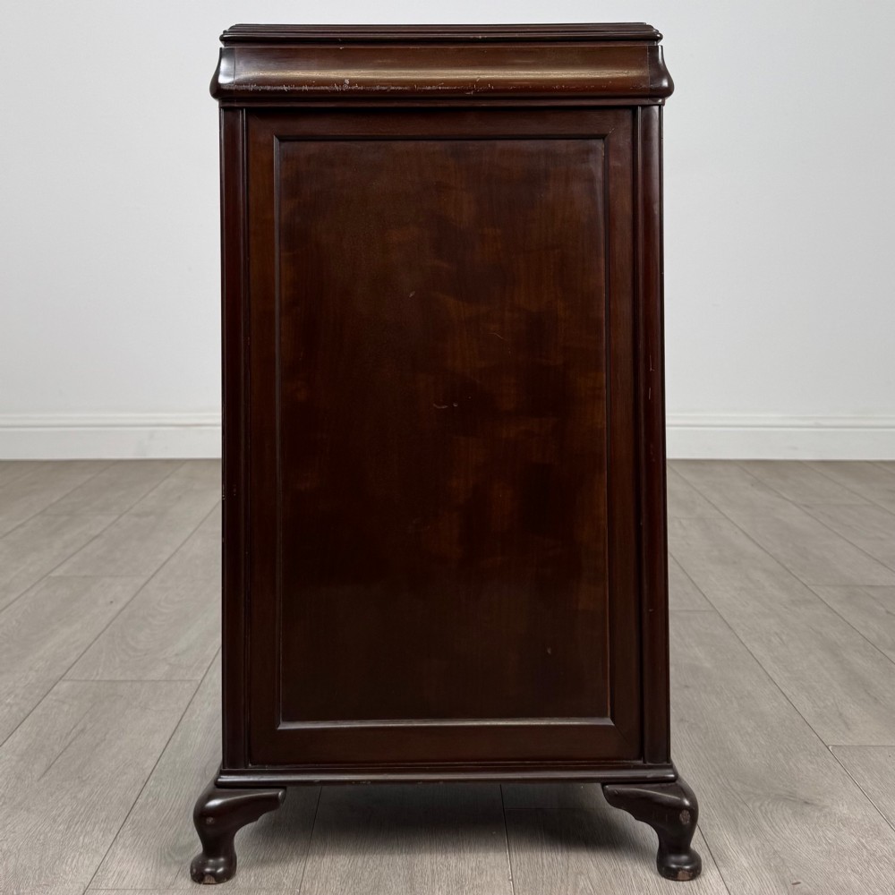 An early 20th-century dark mahogany cupboard featuring two panelled doors with small wooden turned knobs, keyhole escutcheon, and cabriole feet. View VI