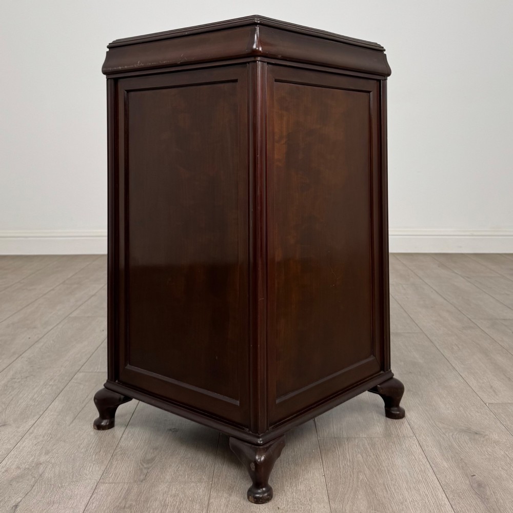 An early 20th-century dark mahogany cupboard featuring two panelled doors with small wooden turned knobs, keyhole escutcheon, and cabriole feet. View VII