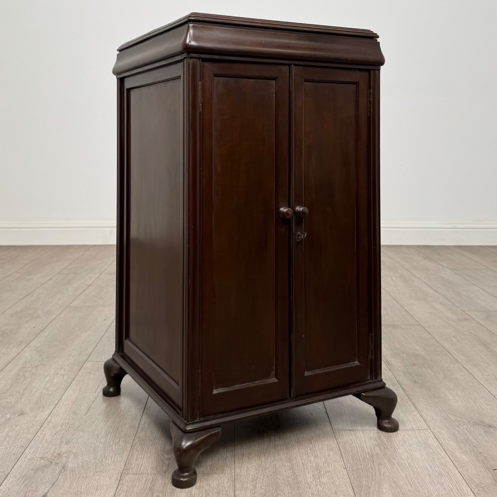 An early 20th-century dark mahogany cupboard featuring two panelled doors with small wooden turned knobs, keyhole escutcheon, and cabriole feet. View IX
