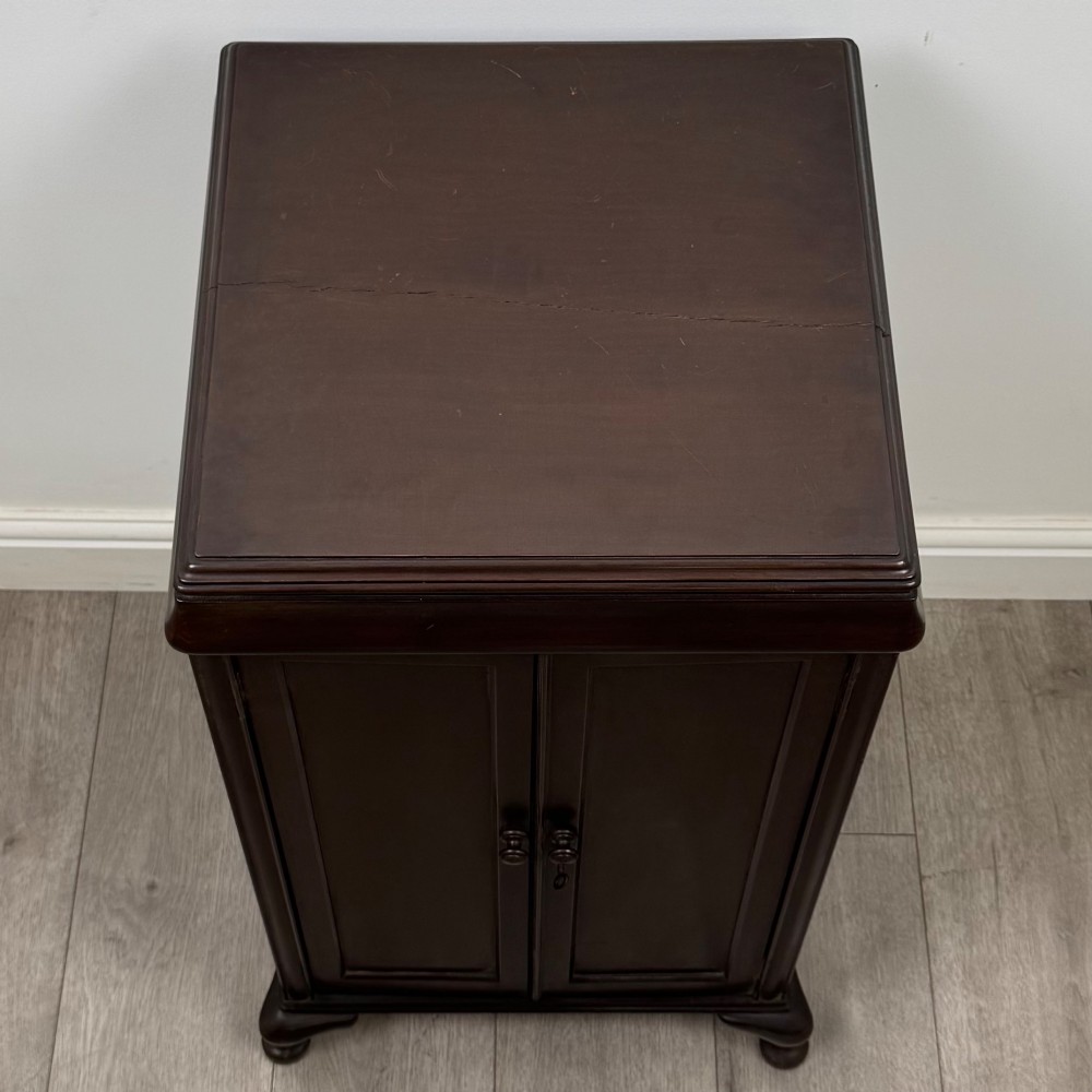 An early 20th-century dark mahogany cupboard featuring two panelled doors with small wooden turned knobs, keyhole escutcheon, and cabriole feet. View X