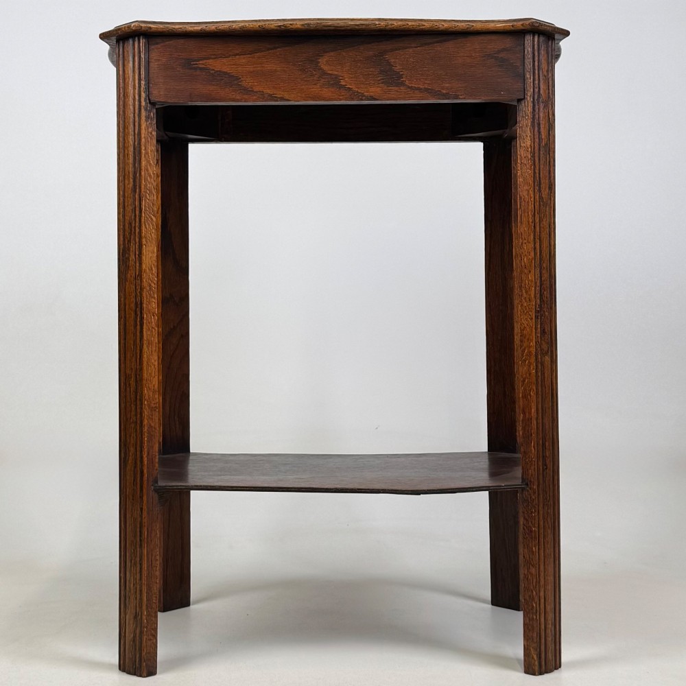 An Edwardian dark oak side table featuring fluted legs, a moulded top, and a lower shelf tier.