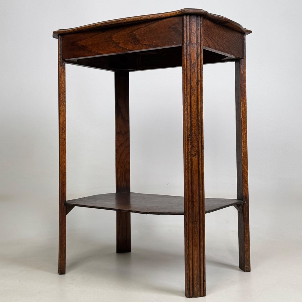 An Edwardian dark oak side table featuring fluted legs, a moulded top, and a lower shelf tier. View II