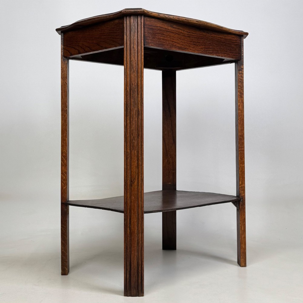 An Edwardian dark oak side table featuring fluted legs, a moulded top, and a lower shelf tier. View IV