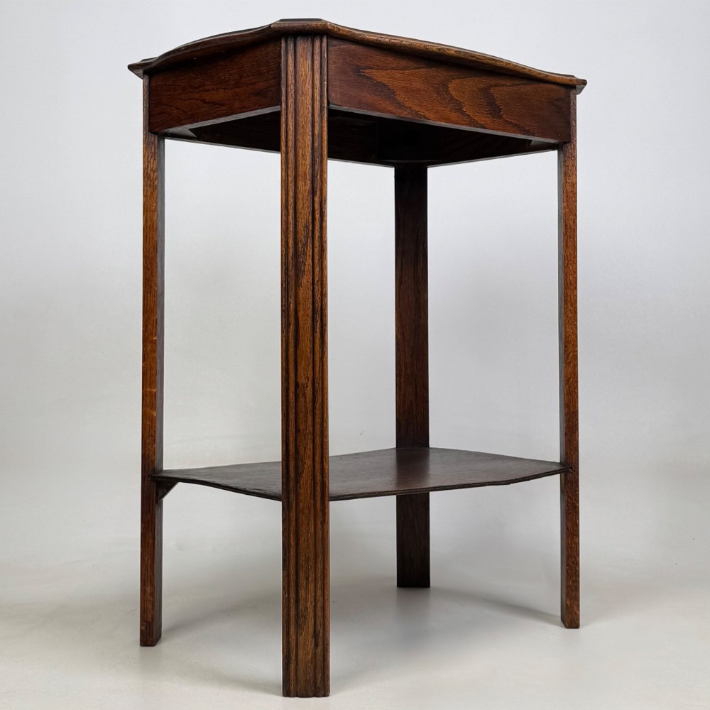 An Edwardian dark oak side table featuring fluted legs, a moulded top, and a lower shelf tier. View VIII