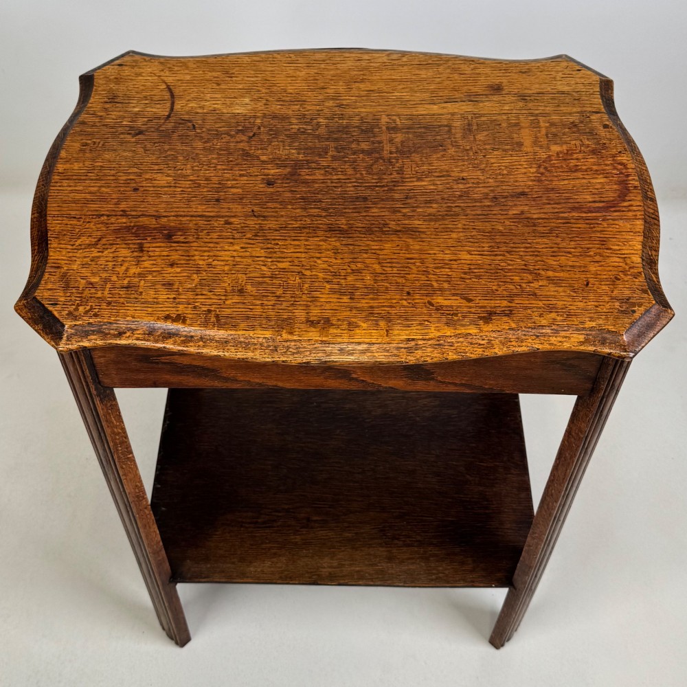 An Edwardian dark oak side table featuring fluted legs, a moulded top, and a lower shelf tier. View IX