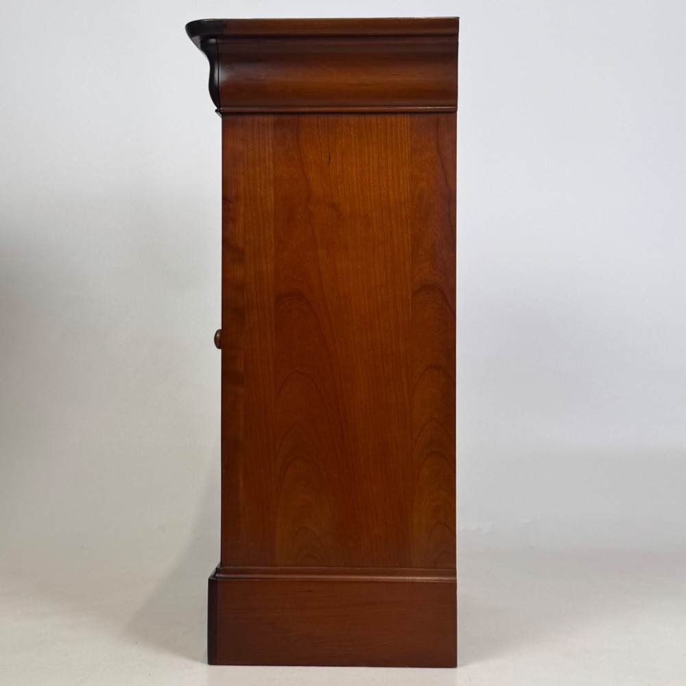 A matching pair of 20th-century mahogany bedside cabinets featuring single panelled doors, turned wooden handles, moulded cornices, and solid plinth bases. View V