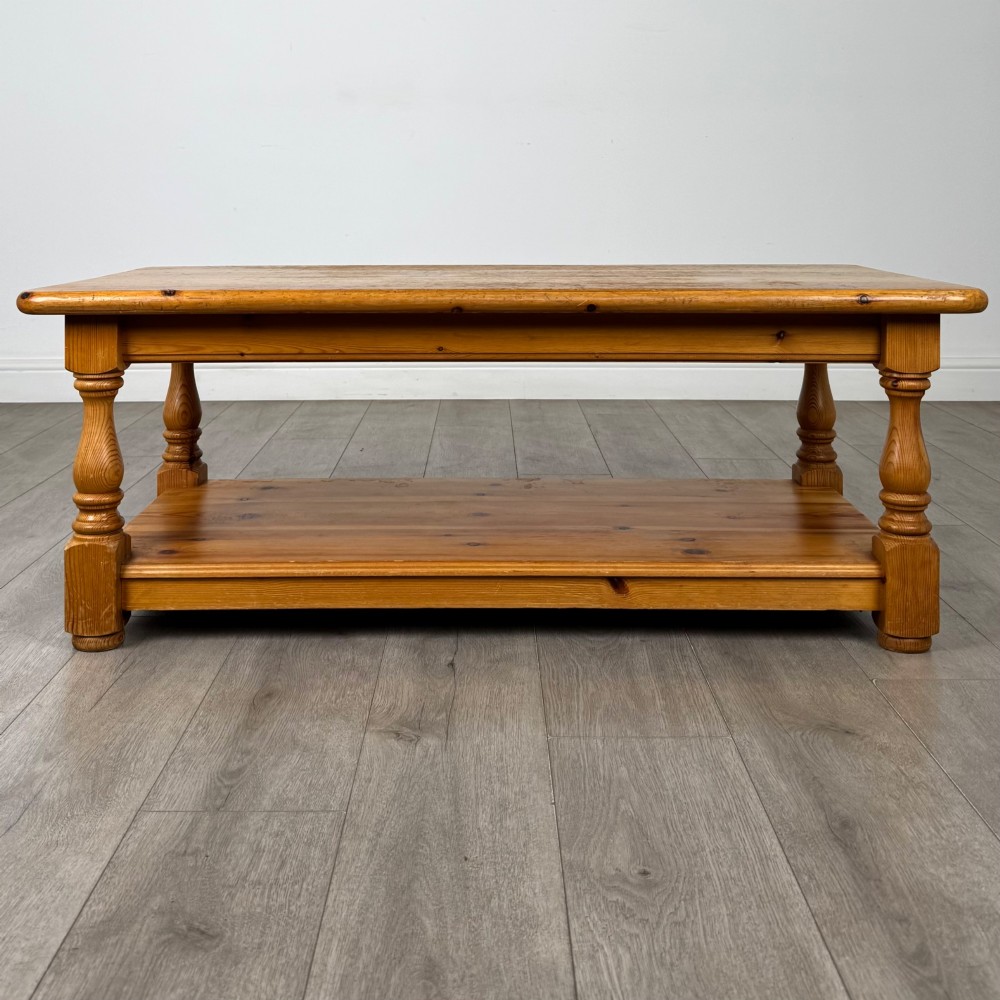 A rectangular warm pine coffee table featuring turned legs and a lower full-length storage shelf. View V