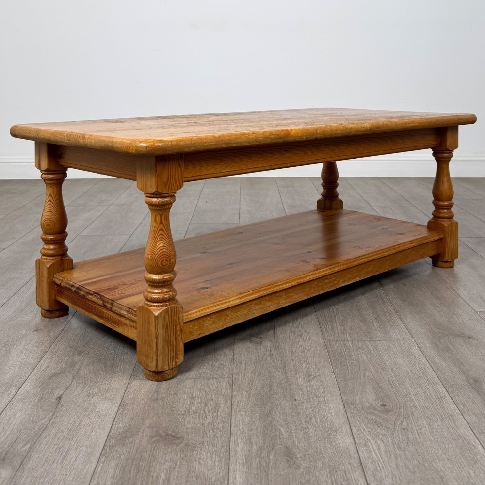 A rectangular warm pine coffee table featuring turned legs and a lower full-length storage shelf. View VIII