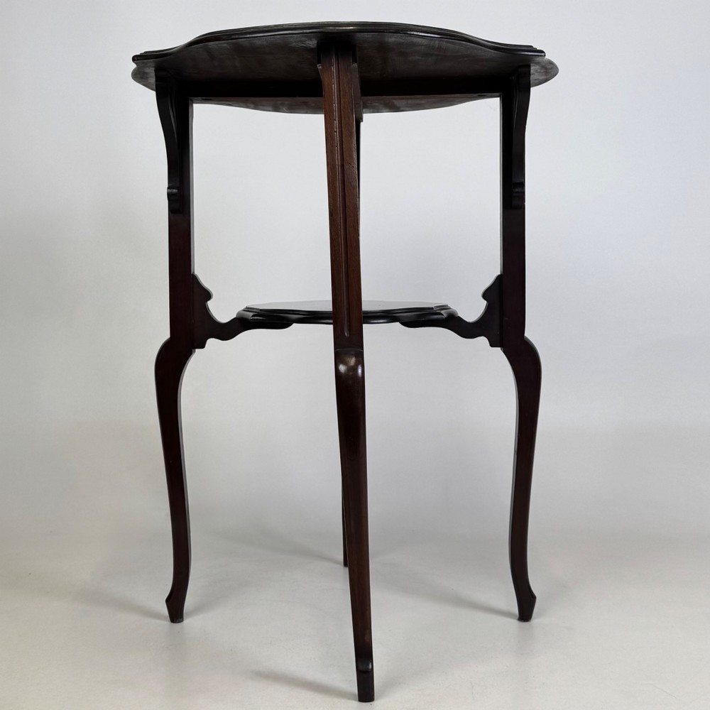 An Edwardian dark mahogany side table featuring a shaped top, pierced carved spandrels, slender cabriole legs, and a lower tier shelf. View II